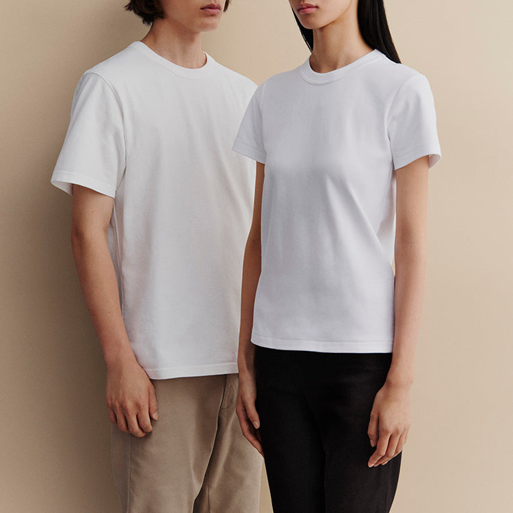 A man and woman modeling plain white crew-neck short-sleeve t-shirts against a beige background.
